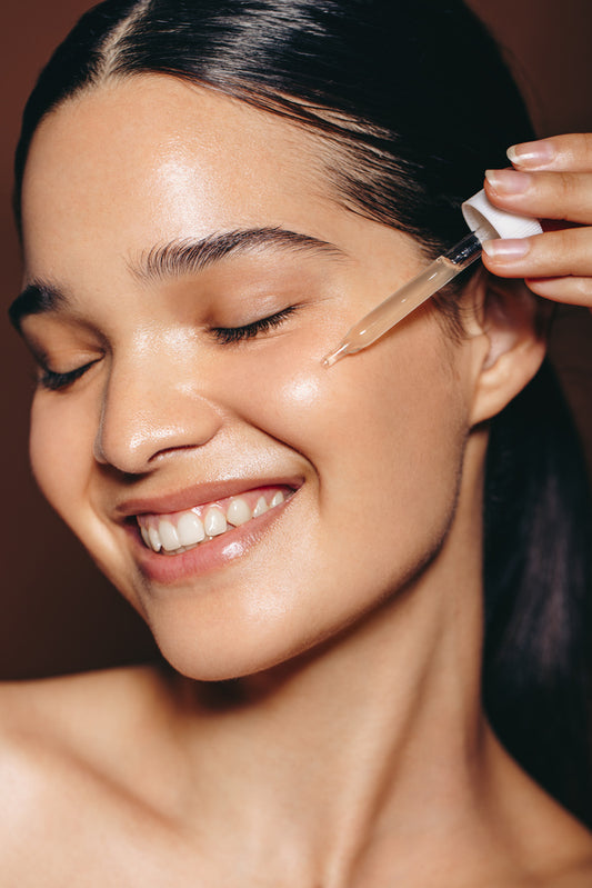 A picture of a happy, smiling woman using retinol serum